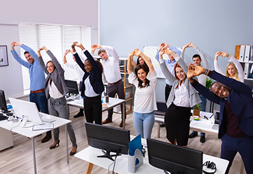 An office team stretching in office together